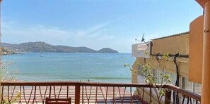 Uma varanda com vista para o mar e colinas ao longe.