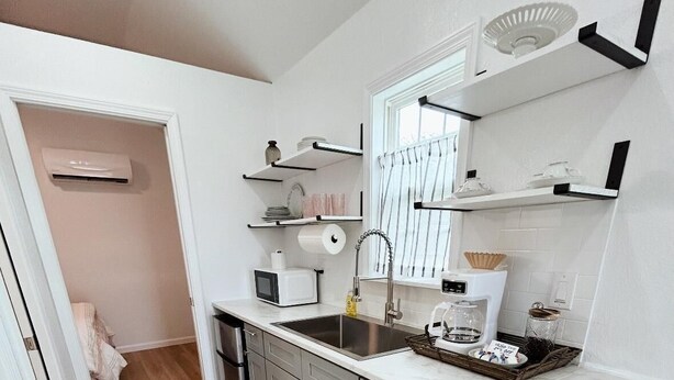 Una cocina moderna con muebles blancos, un lavamanos de acero inoxidable y una encimera blanca.