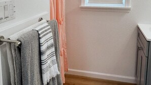 Un baño con cortina de ducha, una ventana y un perchero con toallas.