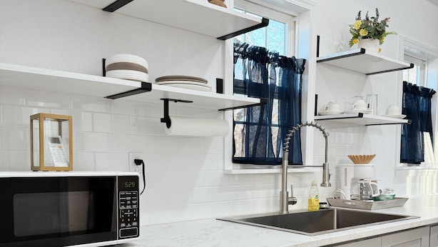 Una cocina moderna con armarios blancos, un microondas integrado, un lavamanos y un refrigerador Galanz.