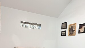 Une chambre avec un grand lit, une table de chevet et une étagère fixée au mur.
