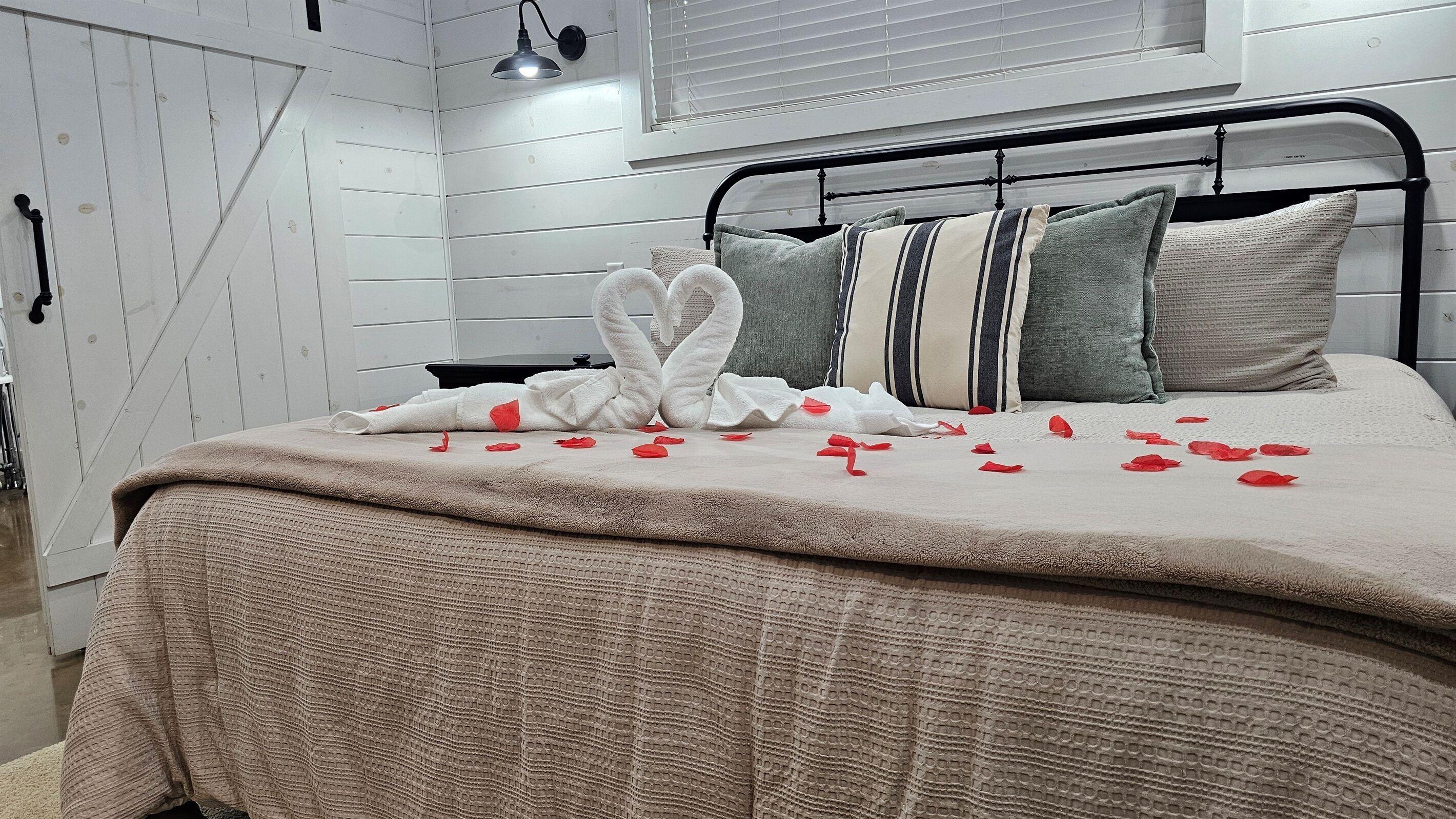 Een net opgemaakt bed met een deken, kussens en een decoratieve zwaan van handdoeken.