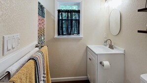Een compacte badkamer met een raam, een wastafel, toilet en handdoekrek.
