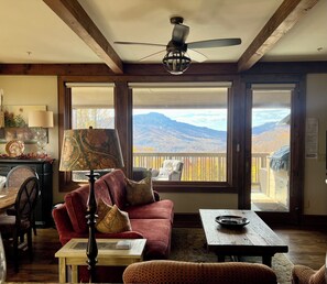 Relax in this mountain-view living room with a large window, ceiling fan, and comfortable seating area.