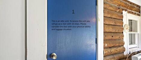 A blue door with a note advising that the unit is an attic and access requires climbing a 10-step stairway.