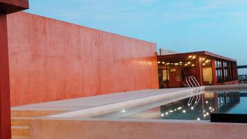 A modern building with a swimming pool, large windows, and a red exterior wall.