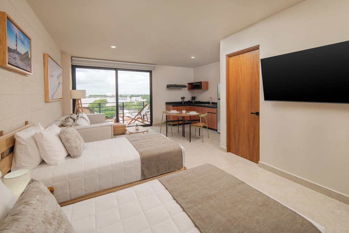 Una habitación de hotel moderna con una cama grande, un escritorio y un balcón con vistas.