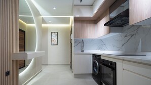 Una cocina moderna con lavadora y secadora integradas, un salpicadero de mármol y una pared decorativa de madera.