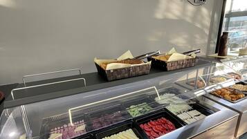 A buffet with various food items, a television mounted on the wall, and a window with natural light.
