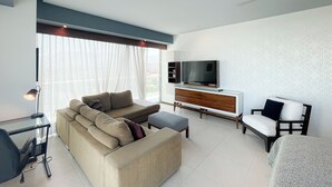 A modern living room with a sectional sofa, a flat-screen TV, a wooden cabinet, and a ceiling fan. - Lujoso Peninsula T3 Frente al Mar (Puerto Vallarta)