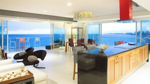 A modern living room with a large glass door leading to a balcony with a city view. - Lujoso Peninsula T3 Frente al Mar (Puerto Vallarta)