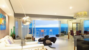 A modern living room with a white sofa, a glass coffee table, and a dining area with chairs and a table. - Lujoso Peninsula T3 Frente al Mar (Puerto Vallarta)