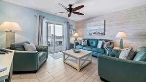 A living room with two green sofas, a white coffee table, and a ceiling fan. - Affordable updated 2BR family retreat with pool (Gulf Shores)