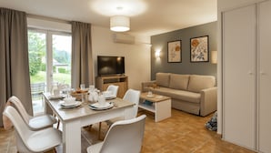 Un salon moderne comprenant un coin repas, un canapé, un téléviseur et des œuvres d’art accrochées aux murs.