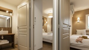 Une chambre d’hôtel avec une coiffeuse en bois, un lit avec une literie blanche, une lampe de chevet et une fenêtre donnant sur un paysage agréable.