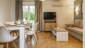 Un salon moderne comprenant un coin repas, un téléviseur à écran plat et un canapé.