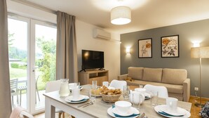 Un coin repas avec une table mise pour le petit-déjeuner, un canapé et un téléviseur en arrière-plan.