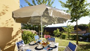 An outdoor patio with a table set for breakfast, including croissants, coffee, and juice.