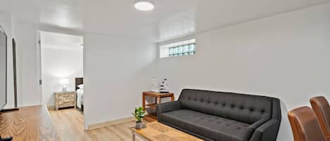 A modern living room with a grey sofa, a wooden coffee table, and a small side table with a lamp.