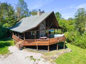 Un rustico chalet con un camino in pietra, un pontile in legno e un’area salotto all’aperto.