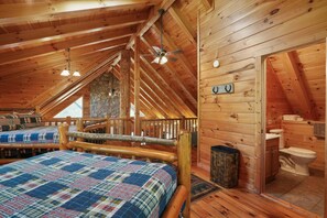Un accogliente rifugio con camera da letto in soppalco, parete in pietra e bagno in legno.