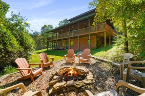 A lodge with a fire pit and Adirondack chairs in a wooded area. - Pine Knoll Lodge | Hocking Hills, Hot Tub, Views (Logan)