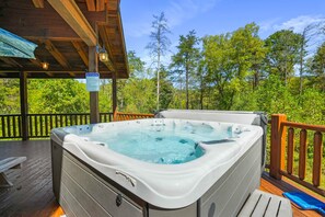 Una vasca idromassaggio su un pontile di legno con vista sugli alberi.