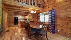 Interno di una baita di legno con zona pranzo, cucina e balcone.