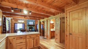 Interno di una baita in legno con angolo cottura, mobili in legno e un'ampia porta di legno.