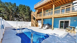 A swimming pool with a wooden deck and a two-story building with a balcony. - Oceanside, Private Pool, Hot Tub, WC960, Blue Heron (Corolla)