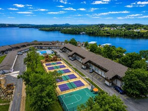 A lakeside property with multiple tennis courts, a swimming pool, and a parking area.