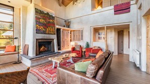 A spacious living room with a fireplace, a large painting, and a cozy seating area. - Panoramic views | Private hot tub | BBQ | Parking (Whistler)