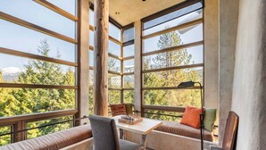 A room with large windows, a wooden table, and a chessboard. - Panoramic views | Private hot tub | BBQ | Parking (Whistler)