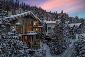 Een meerlaags hotel met balkon, omringd door met sneeuw bedekte bomen.