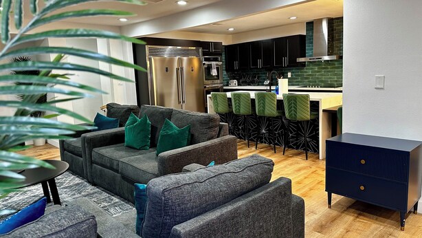 Un salon moderne avec un canapé gris, des coussins verts et un meuble bleu foncé.