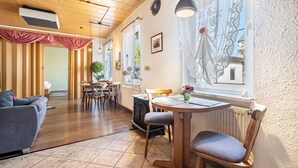 A cozy room with a wooden ceiling, a dining area with a table and chairs, a sofa, and a radiator. - Holiday Apartment 'Ferienhaus Nestwärme' with Private Terrace, Private Garden and Wi-Fi (Calau)