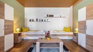 A modern room with two beds, a wooden coffee table, and built-in shelving with decorative items. - Holiday Apartment 'Ferienhaus Nestwärme' with Private Terrace, Private Garden and Wi-Fi (Calau)