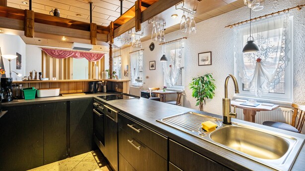 A modern kitchen with a central island, wooden beams, pendant lights, and a view of the dining area. - Holiday Apartment 'Ferienhaus Nestwärme' with Private Terrace, Private Garden and Wi-Fi (Calau)
