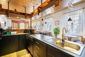 A modern kitchen with a central island, wooden beams, pendant lights, and a view of the dining area. - Holiday Apartment 'Ferienhaus Nestwärme' with Private Terrace, Private Garden and Wi-Fi (Calau)