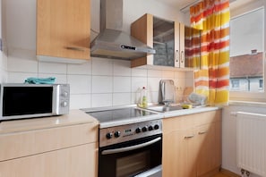 Una cocina con microondas, estufa, horno y armarios de madera.