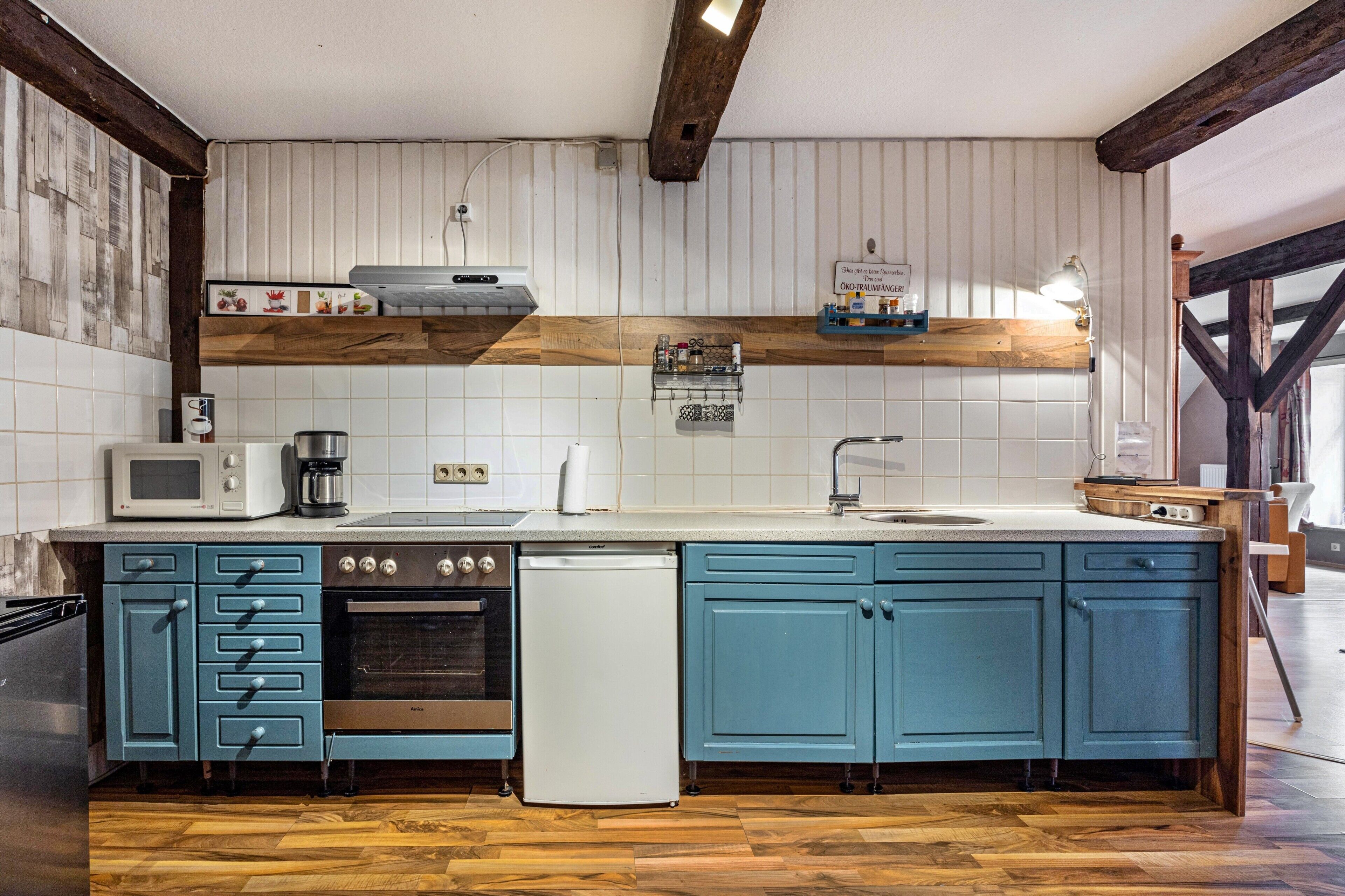 A kitchen with wooden beams, a microwave, stove, and a dishwasher.