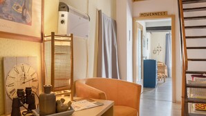 Una habitación con un escritorio de madera, una silla, un reloj, un calentador y una puerta con la etiqueta 'MOWENNEST'.