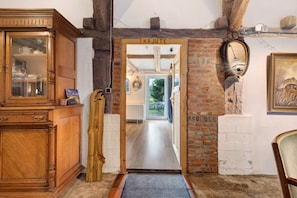 Un meuble en bois doté de portes en verre, une porte en bois portant l’inscription « KAJUTE », et un mur de briques sur lequel est accroché un miroir.