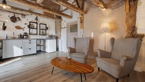 Una cocina moderna con armarios blancos, una mesa de comedor de madera y un sillón a cuadros.