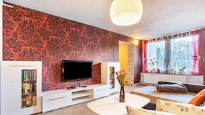 A modern living room with a flat-screen TV, a bookshelf, a sofa, and a coffee table.
