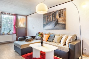 A modern living room with a sofa, a coffee table, a floor lamp, and a large painting on the wall.