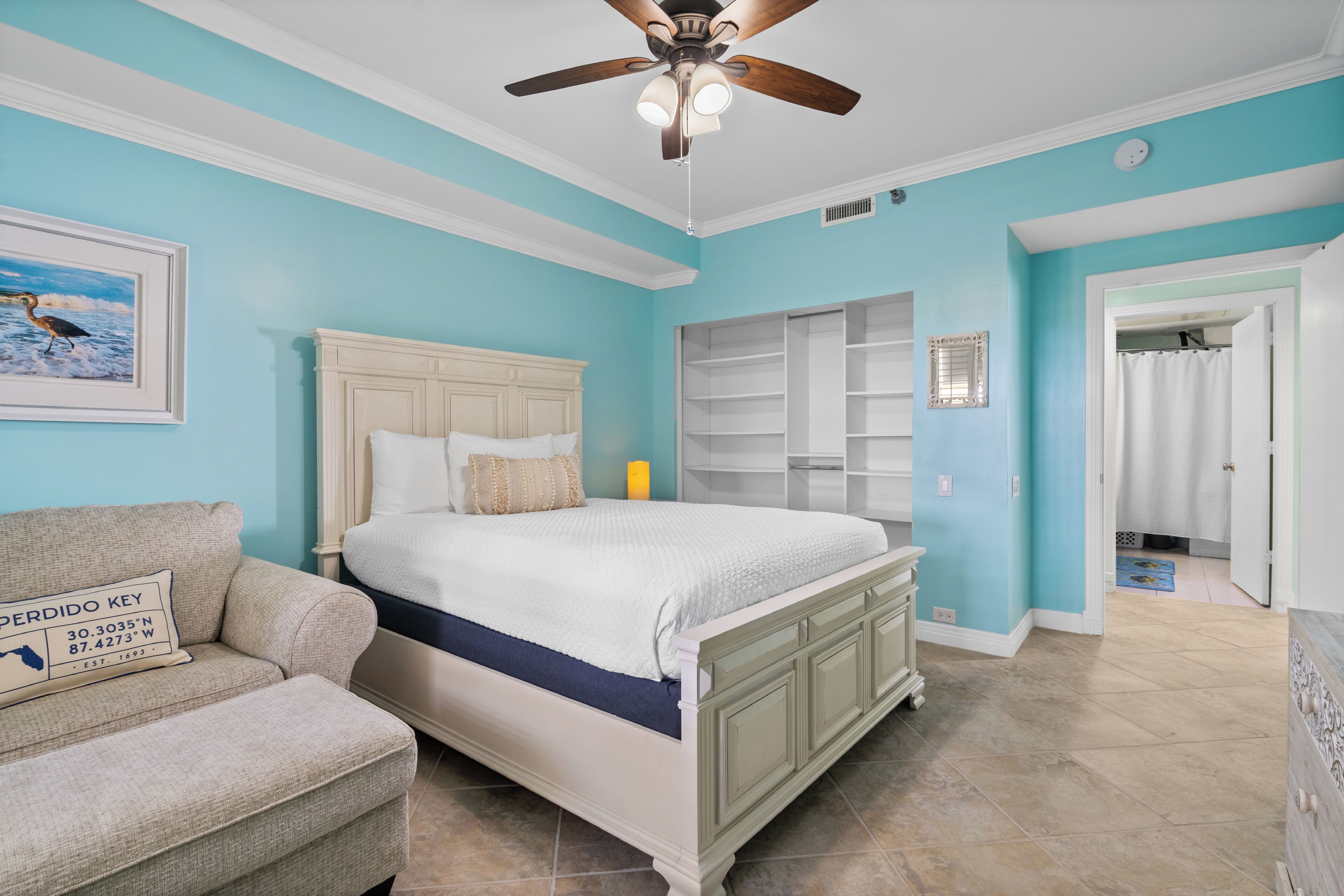 A bedroom with a bed, a ceiling fan, a nightstand, and a chair.