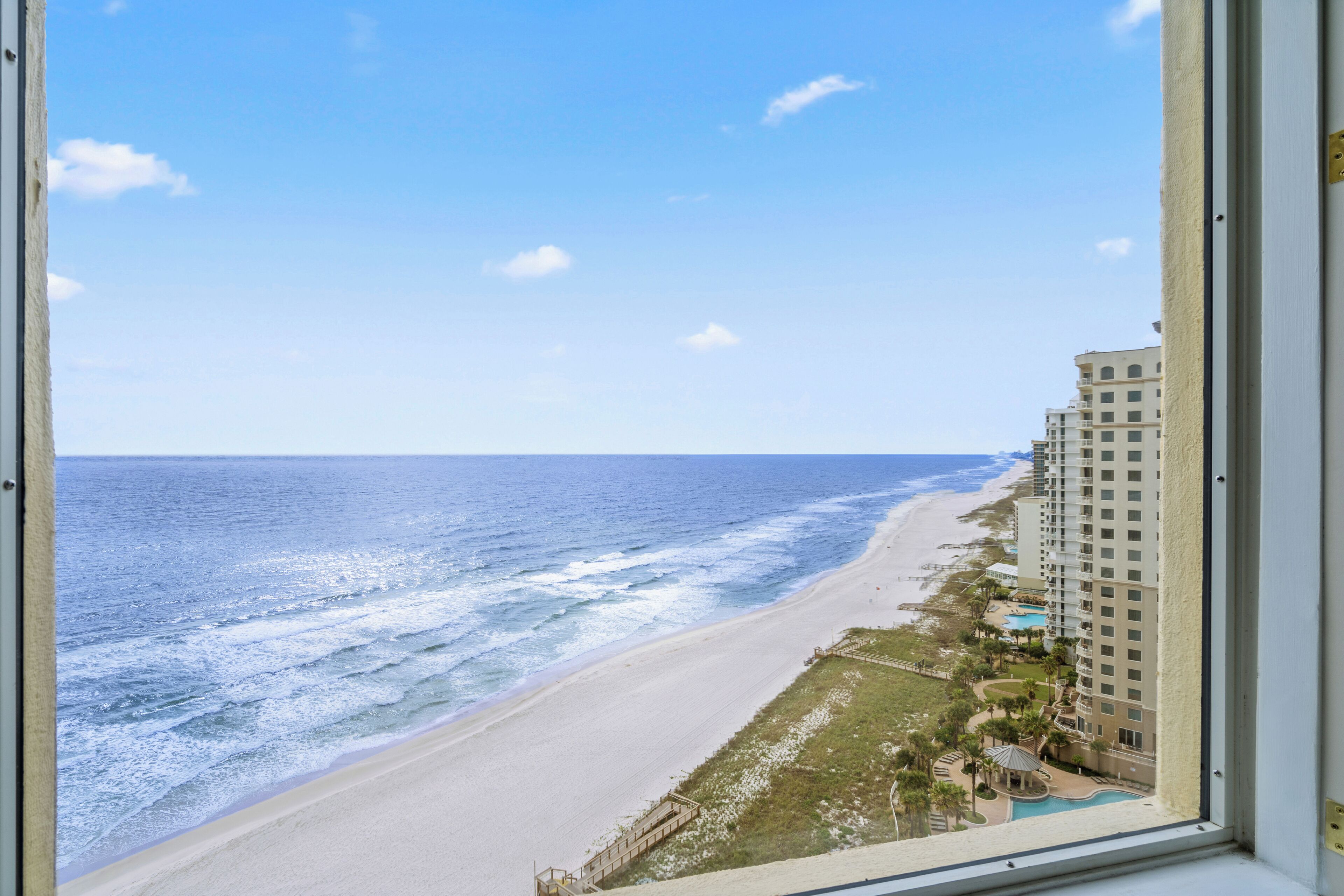A view of a beach with a hotel in the background.