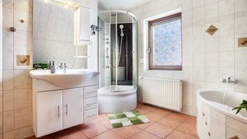 Un baño con ducha, lavamanos, bañera y ventana con vistas.