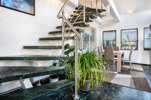 Un intérieur moderne avec un escalier, un coin repas et des plantes en pot.